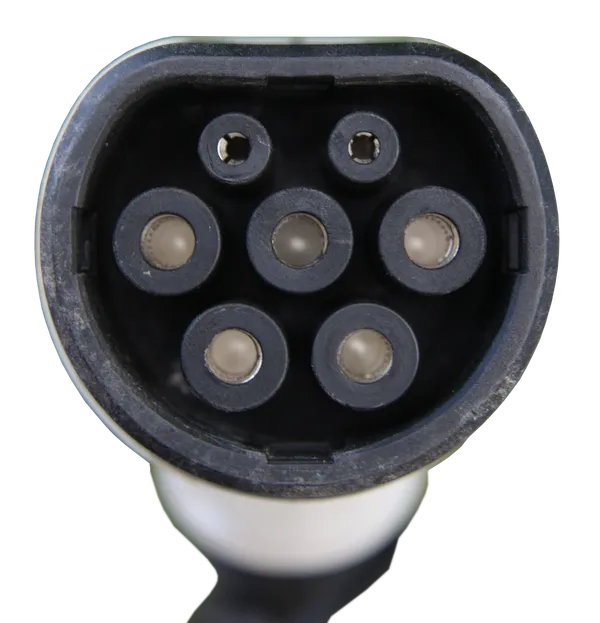 Vue de face d'un connecteur de recharge Type 2 : sept contacts, dont cinq de forte section disposés en cercle et deux de petit diamètre en partie haute, dans une embase dont le bord supérieur est aplati.
